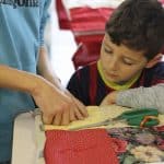 Kindergarten students and eighth graders worked in pairs to knot comforters.