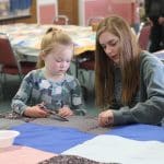 Kindergarten students and eighth graders worked in pairs to knot comforters.