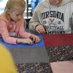 Kindergarten students and eighth graders worked in pairs to knot comforters.