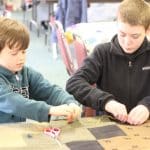 Kindergarten students and eighth graders worked in pairs to knot comforters.