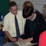 Students look at the old book sent to Yoder from Strasbourg, France, by a reader of his book, "Margaret's Print Shop."