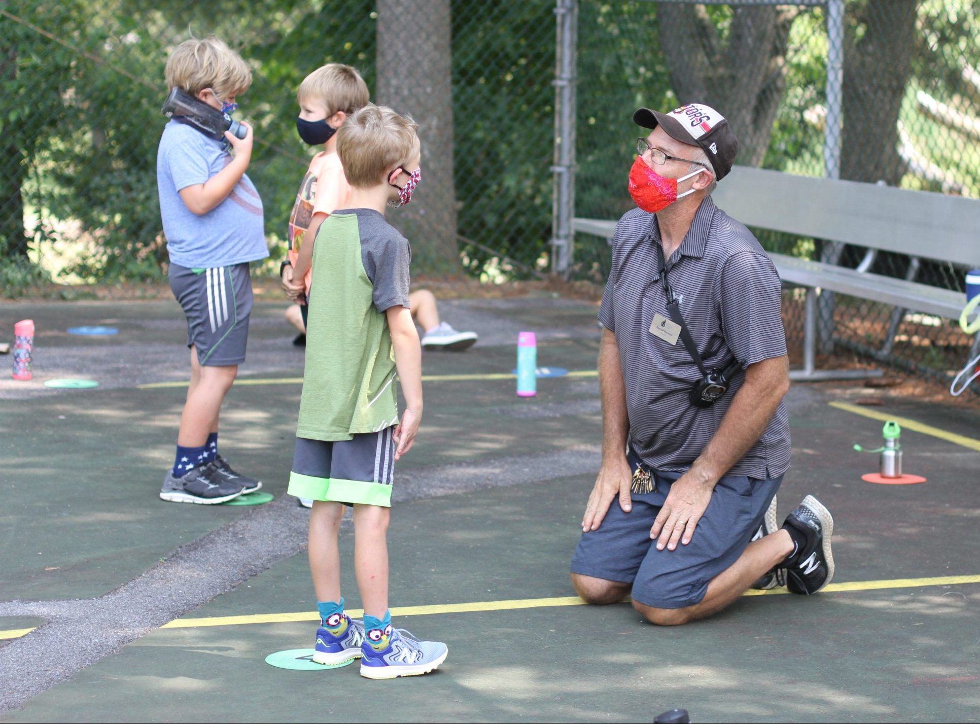 Kendal Bauman gets at eye level with a first grade student during PE.