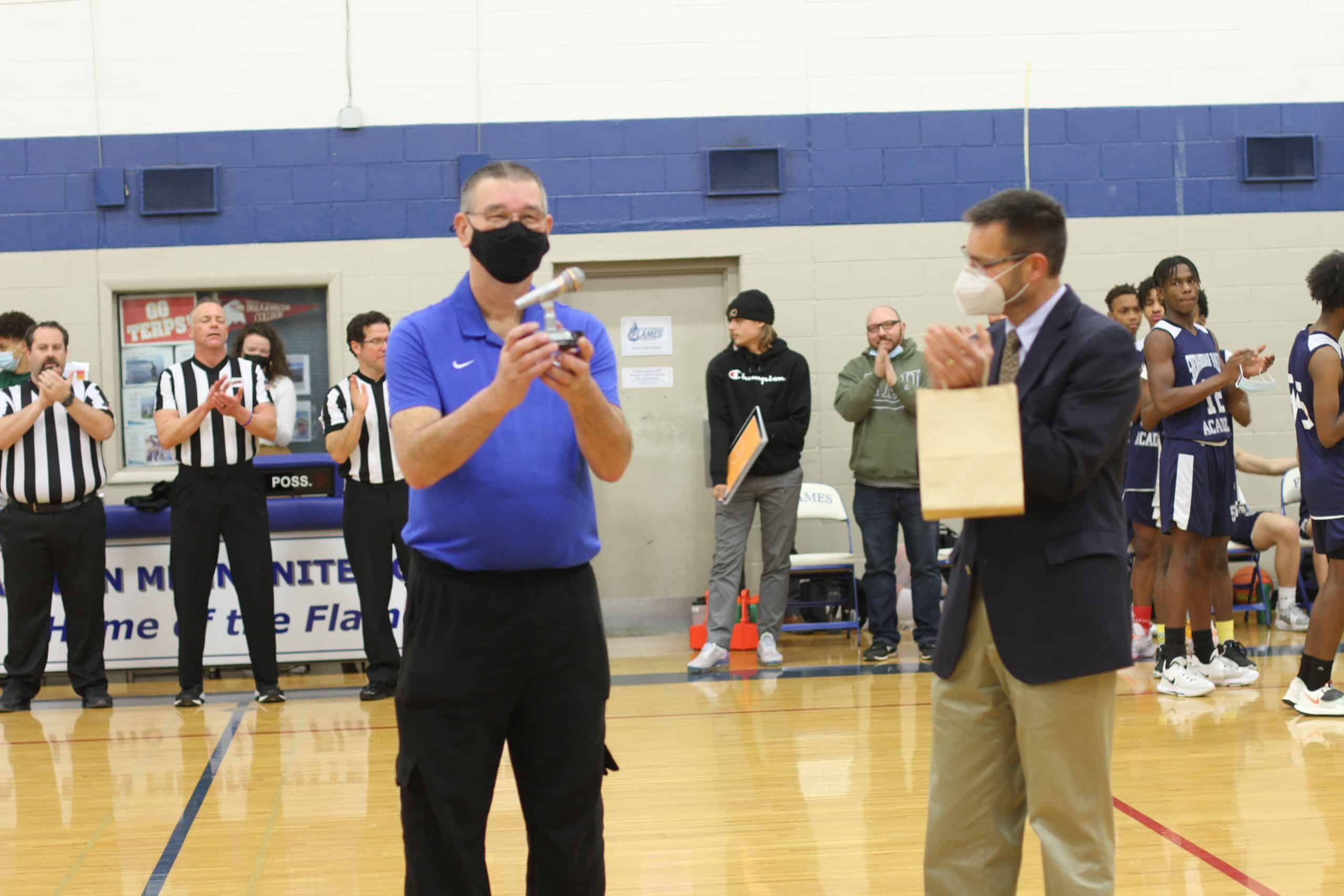 Gene Meiser is honored with a "golden microphone" at his last game as announcer and scoreboard operator.